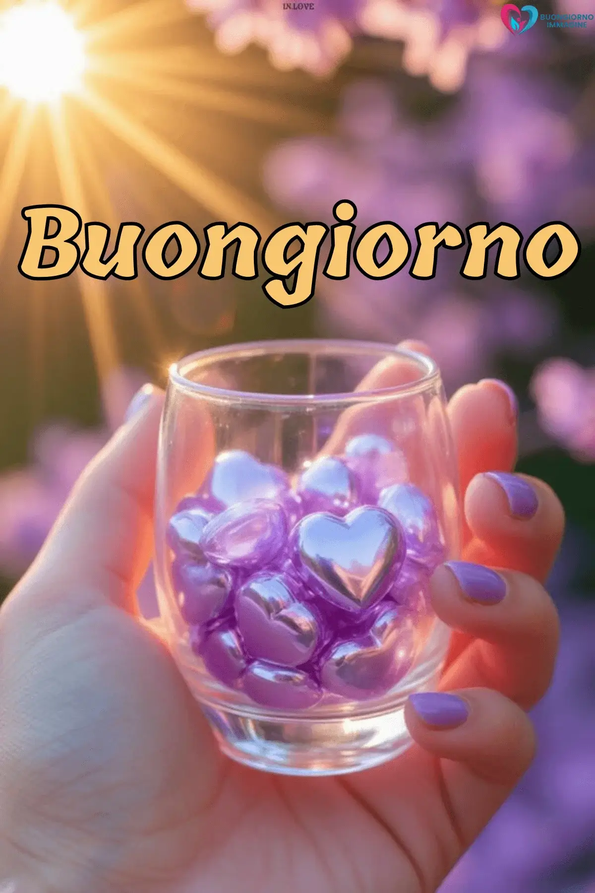 Mano con unghie lilla regge un bicchiere pieno di cuori viola al sole, buongiorno cuore immagini gratis per WhatsApp