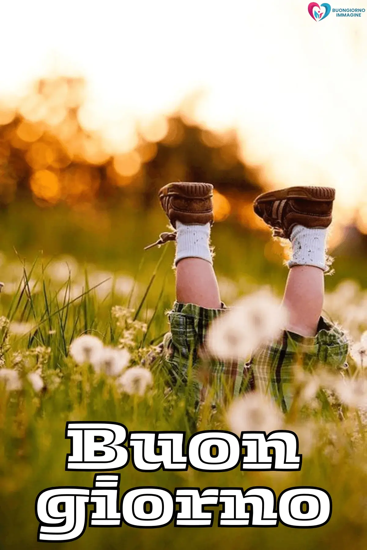 Bambino sdraiato in un prato con i piedini alzati tra i fiori, buongiorno bambini, immagini gratis per WhatsApp